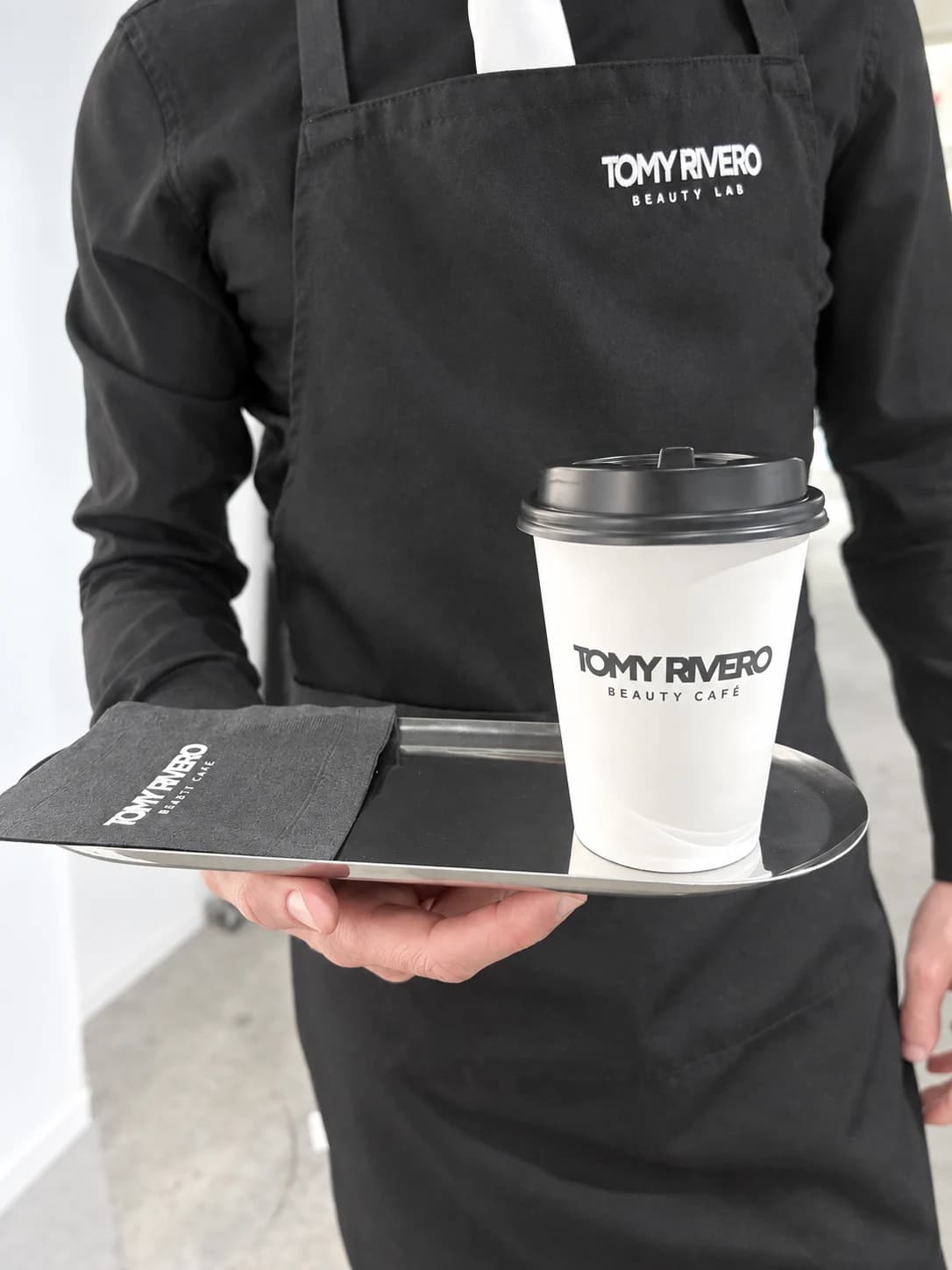 Beauty Cafe team member serving a branded coffee on a tray