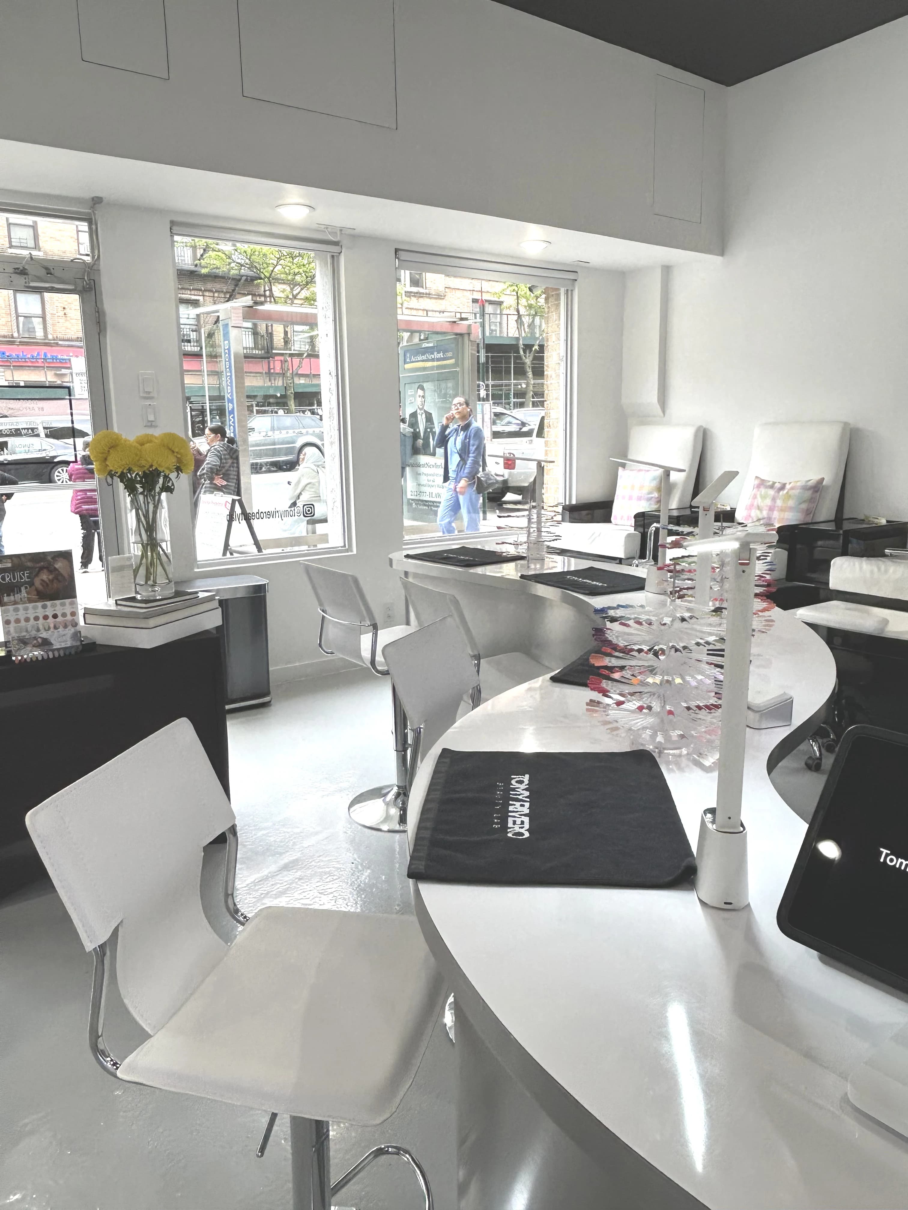 The bright Beauty Lab interior with white manicure tables and seating beside the front windows