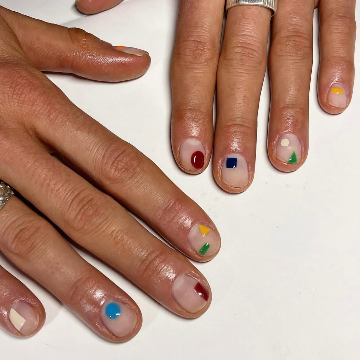 Minimalist nude manicure with colorful hand-painted geometric shape accents
