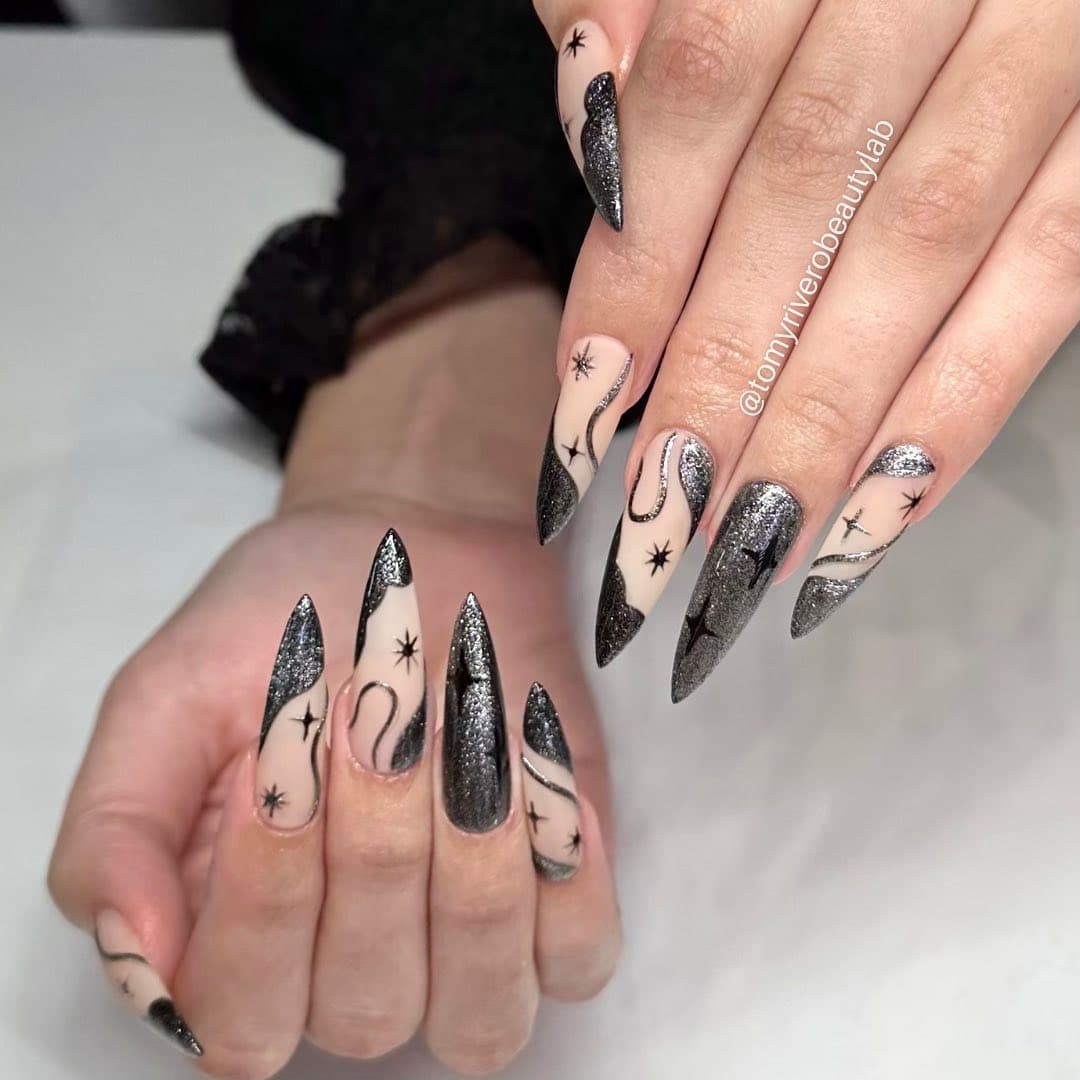 Black and silver glitter stiletto nails with hand-painted star and swirl line art