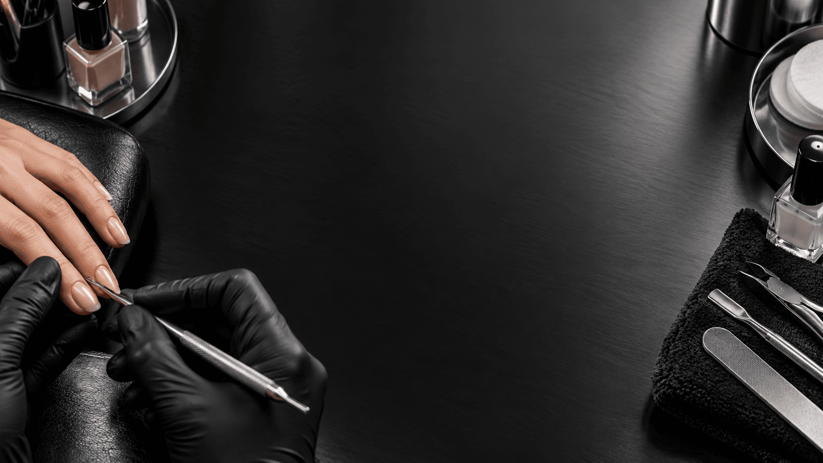 Nail artist in black gloves performing a manicure, framed by professional tools on a dark metallic surface