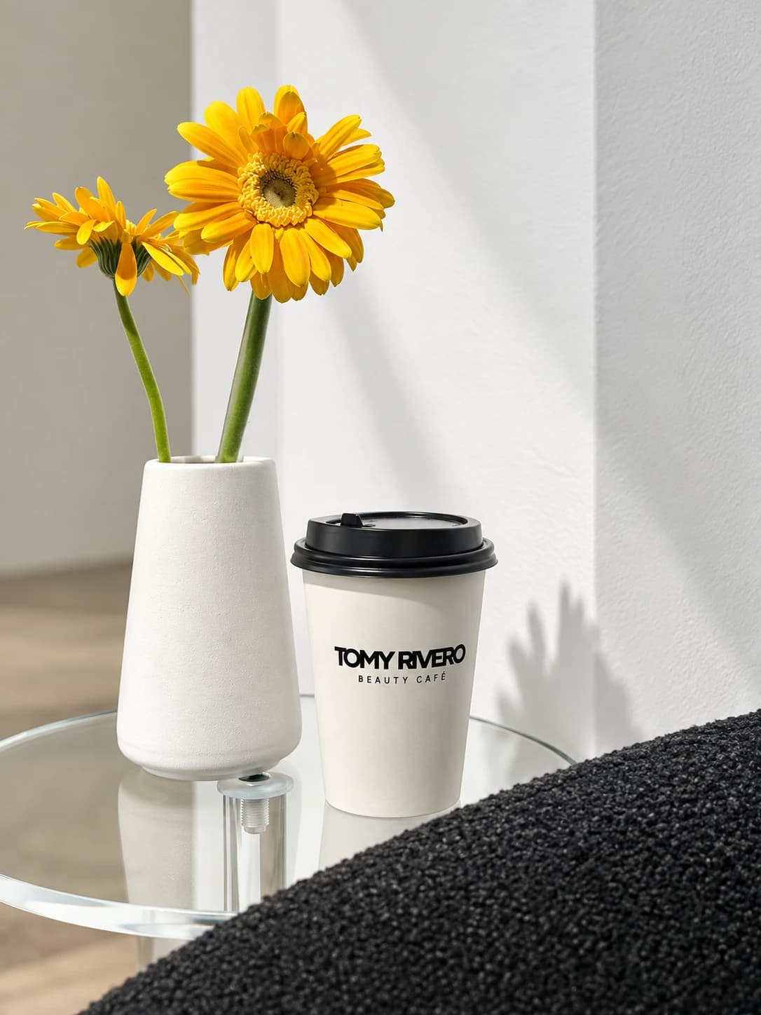 Branded Beauty Cafe coffee beside yellow flowers on a glass table