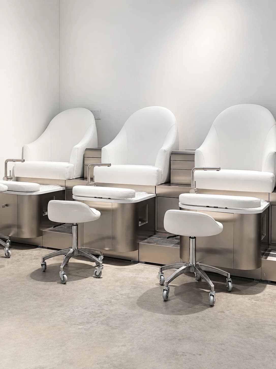 Row of white pedicure chairs and foot basins in the Tomy Rivero Beauty Cafe studio