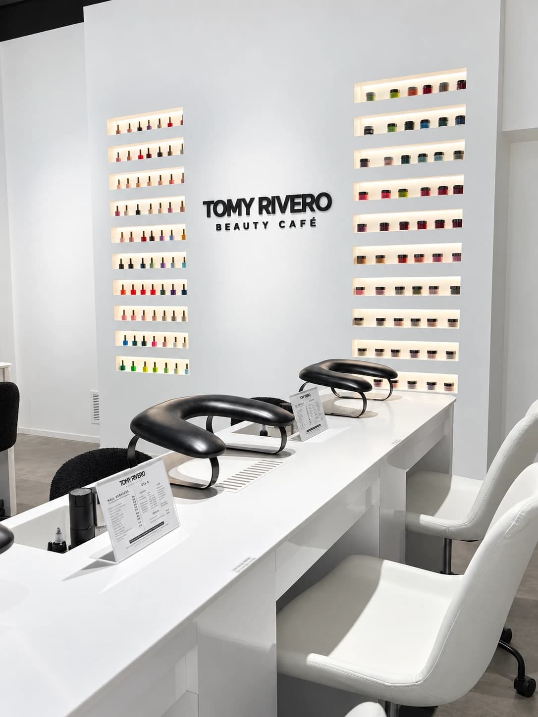 Tomy Rivero Beauty Cafe wordmark mounted between the illuminated nail polish shelves