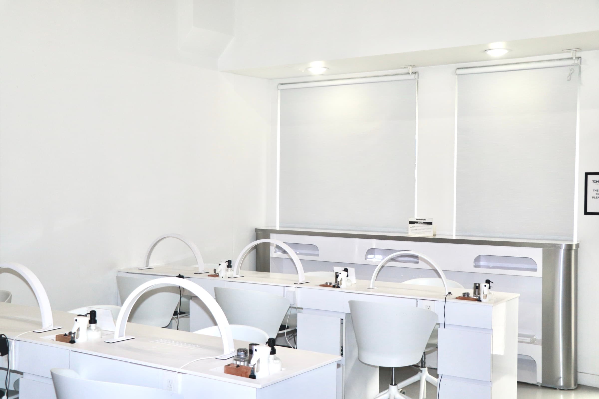 Row of white manicure stations with arched task lighting