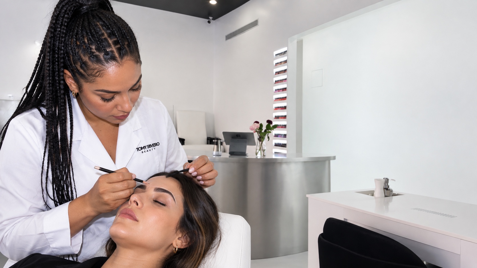 Especialista con bata blanca de Tomy Rivero Beauty diseñando la forma de una ceja
