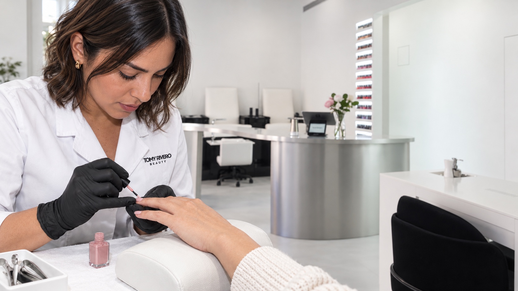 Especialista con bata blanca de Tomy Rivero Beauty haciendo una manicura en un salón iluminado